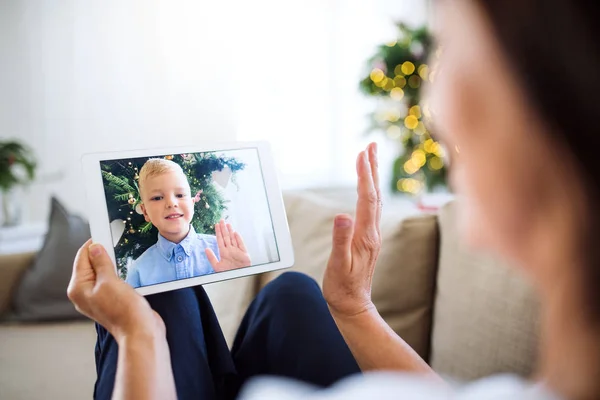 Una abuela con tableta haciendo videocall con su nieto pequeño en Navidad . — Foto de Stock