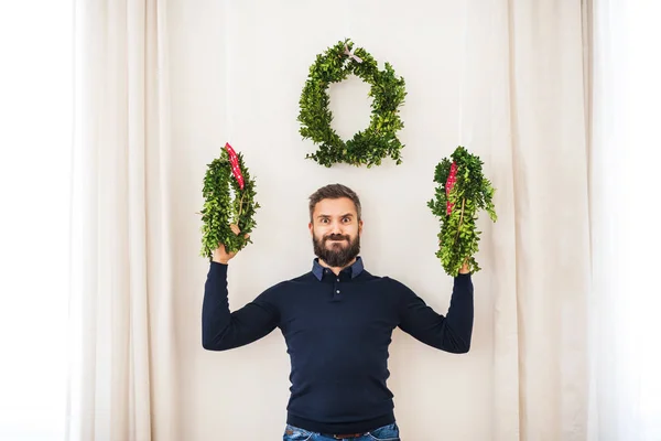 Een man van de hipster met groene kransen bij Kerstmis, plezier. — Stockfoto
