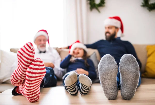 Mała dziewczynka z ojca i dziadka siedzi na kanapie w okresie Bożego Narodzenia. — Zdjęcie stockowe