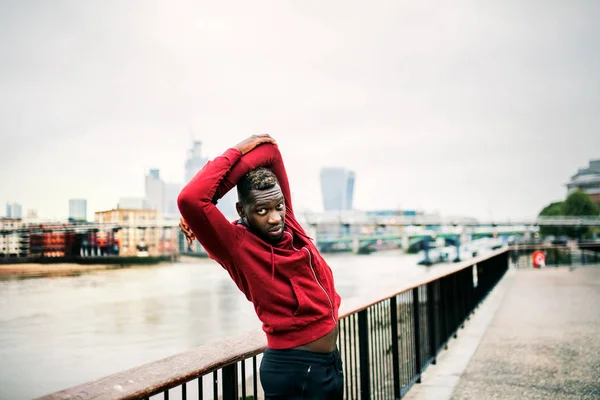 年轻的运动黑人赛跑者做伸展在桥梁外面在城市. — 图库照片