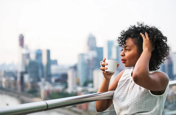 Ritratto ravvicinato di una donna in piedi su una terrazza, che beve caffè . — Foto Stock