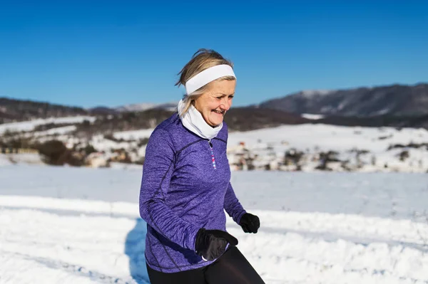 Mujer mayor corriendo en la naturaleza invernal. Copiar espacio . — Foto de Stock