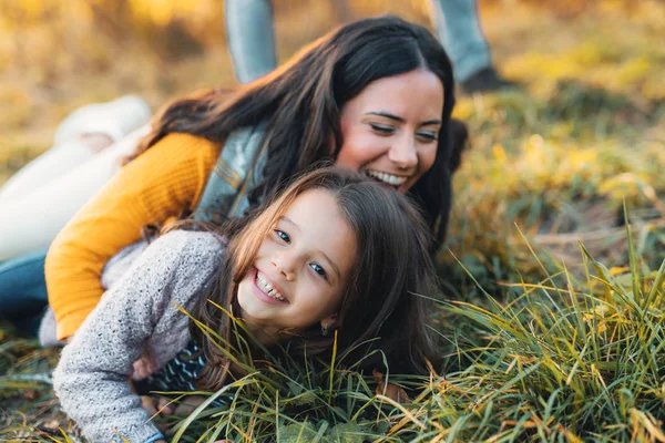 Ett porträtt av ung mamma med en liten dotter i höstens natur. — Stockfoto