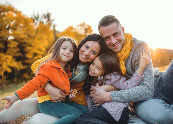 A portrait of young family with two small children in autumn nature at sunset. — Stock Photo, Image