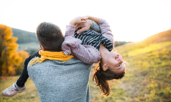 A rear view of young father having fun with a small daughter in autumn nature. — Stock Photo, Image