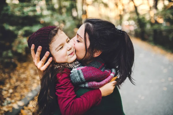 A young mother with a toddler daughter hugging and kissing in forest in autumn nature. — Stock Photo, Image