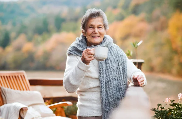 在一个阳光明媚的秋天, 一位老年妇女坐在户外的露台上. — 图库照片