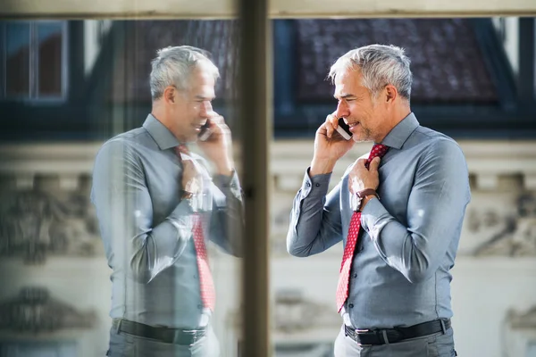 Dojrzałe biznesmen z smartphone stojąc na tarasie w mieście, rozmowa telefoniczna. — Zdjęcie stockowe