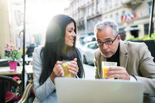 Man and woman business partners with laptop sitting in a cafe in city, talking. — Stock Photo, Image