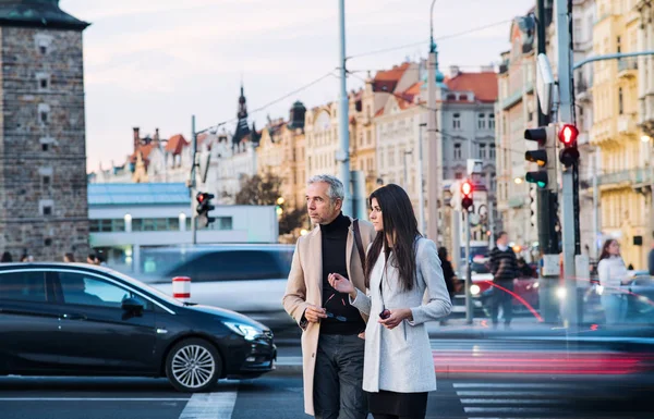 Férfi és nő üzleti partnerek, átkelés a forgalmas úton a Prága. — Stock Fotó