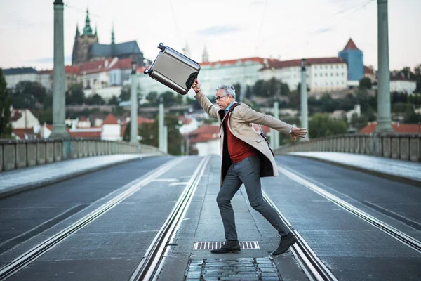 Счастливый взрослый бизнесмен с чемоданом, переходящим дорогу в Праге . — стоковое фото
