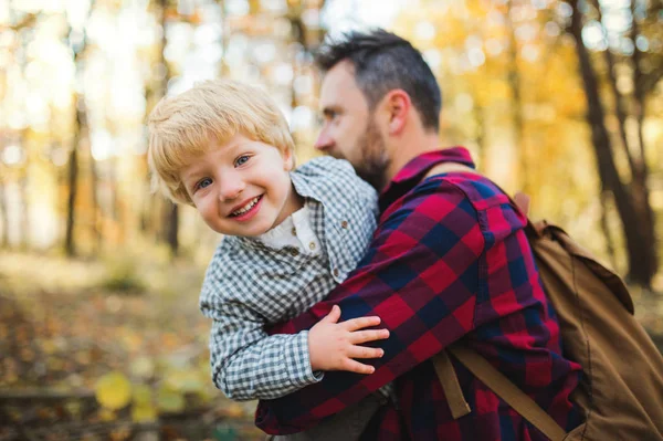 A mature father holding a toddler son in an autumn forest, having fun. — Stock Photo, Image