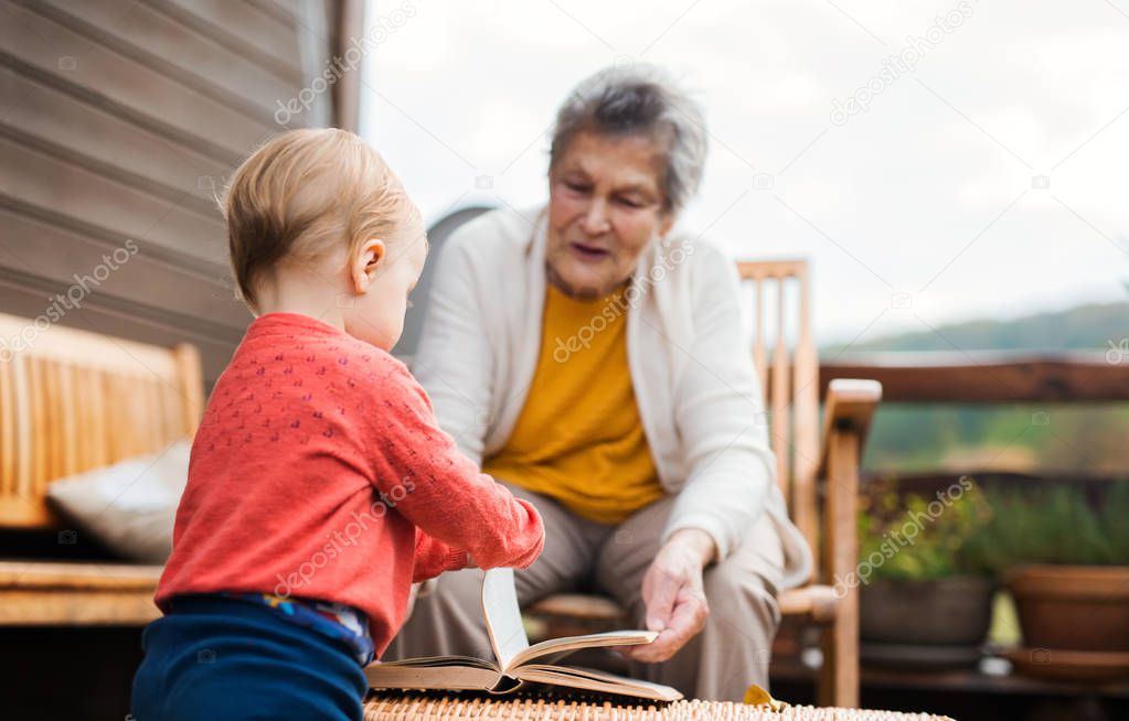 Elderly woman with a toddler great-grandchild on a terrace in autumn.
