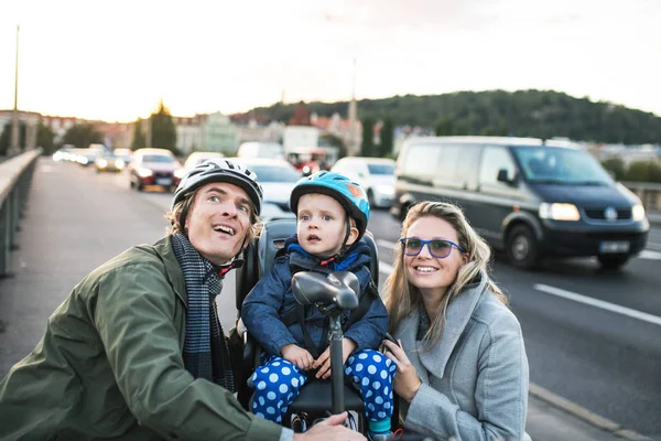 야외 시에서에서 젊은 부모와 함께 자전거 좌석에 앉아 작은 유아 소년. — 스톡 사진