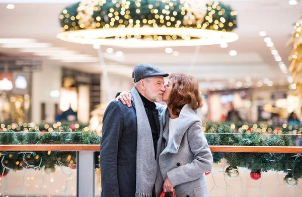 Un heureux couple de personnes âgées debout dans le centre commercial, embrasser . — Photo