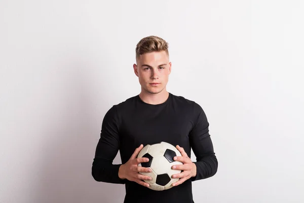 Retrato de um jovem com bola de futebol num estúdio. Espaço de cópia . — Fotografia de Stock