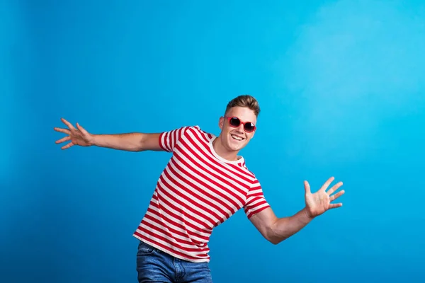 Молодий чоловік з червоними сонцезахисними окулярами стоїть в студії, розважаючись . — стокове фото