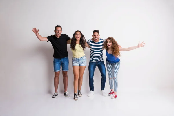 Retrato de jovem grupo alegre de amigos de pé braço a braço em um estúdio . — Fotografia de Stock
