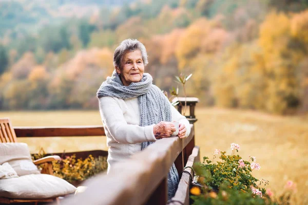 Una anciana parada al aire libre en una terraza en un día soleado en otoño . —  Fotos de Stock