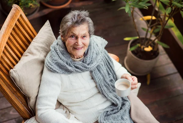 Une vue de dessus de la femme âgée avec une tasse de café assis à l'extérieur sur une terrasse  . — Photo