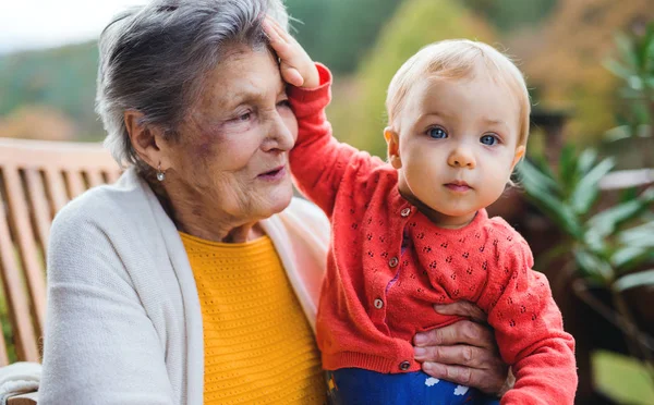 秋の幼児の曾孫でテラスに座っている年配の女性. — ストック写真