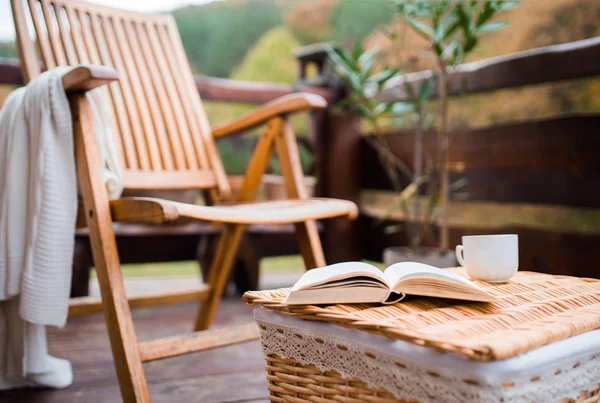 Uma cadeira de madeira e um livro sobre uma cesta em um terraço em um dia ensolarado no outono . — Fotografia de Stock