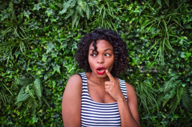 Bush yaprakları yeşil arka planı duran siyah bir kadın portresi.