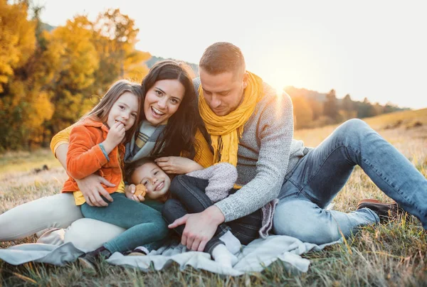 Um retrato de uma jovem família com duas crianças pequenas na natureza do outono ao pôr do sol . — Fotografia de Stock
