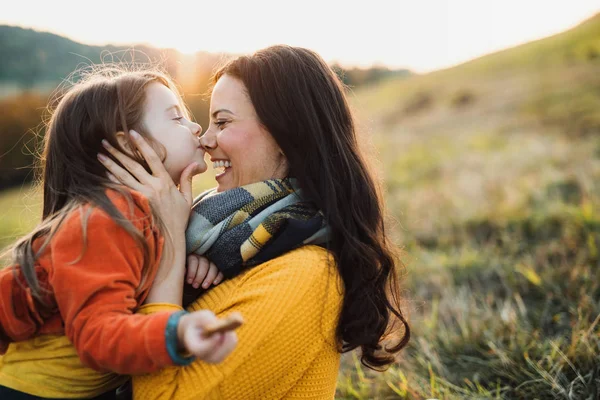 Ett porträtt av ung mor med en liten dotter i höst natur vid solnedgången. — Stockfoto