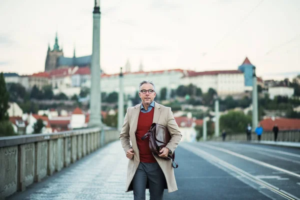 Uomo d'affari maturo con borsa a piedi su un ponte nella città di Praga . — Foto Stock