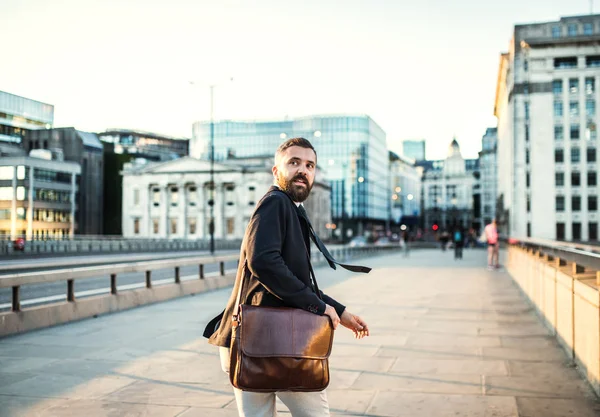 Una vista trasera del hombre de negocios hipster con una bolsa corriendo por la calle en la ciudad . — Foto de Stock