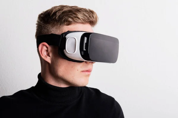 Portrait of a young man with virtual reality goggles in a studio. — Stock Photo, Image
