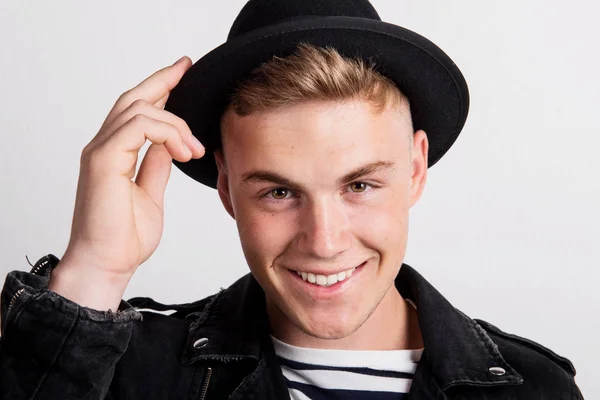 Close-up portrait of a confident young man with a black hat in a studio. — Stock Photo, Image
