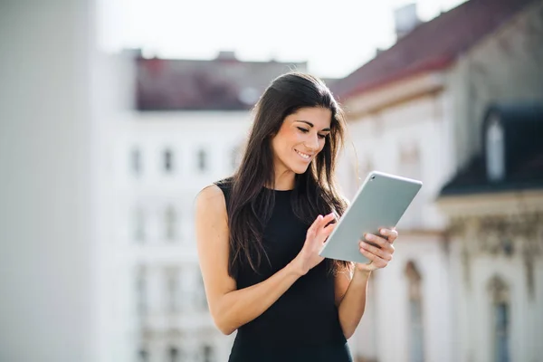 Giovane donna d'affari con tablet in piedi su una terrazza fuori da un ufficio in città . — Foto Stock