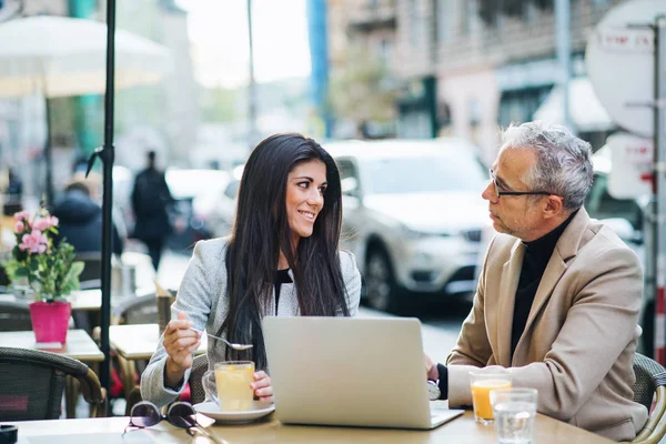 Homem e mulher parceiros de negócios com laptop sentado em um café na cidade, conversando . — Fotografia de Stock