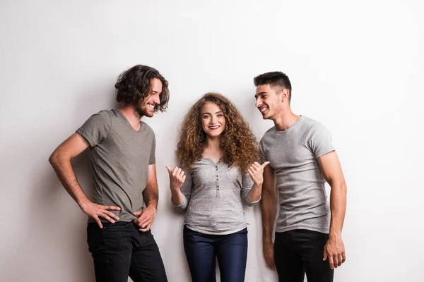 Retrato de niña alegre con dos amigos varones de pie en un estudio . — Foto de Stock