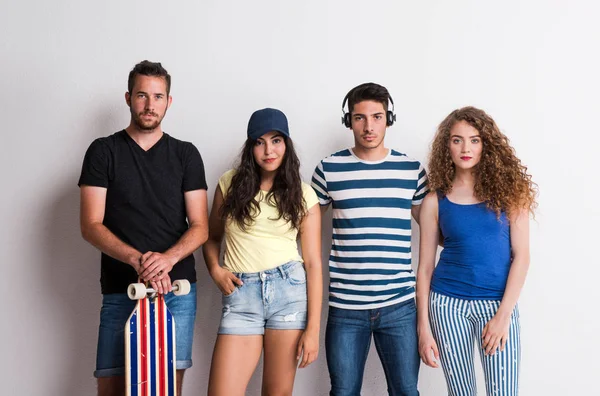 Retrato de jovem grupo alegre de amigos com longboard de pé em um estúdio . — Fotografia de Stock