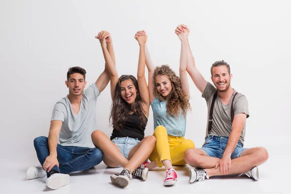 Retrato de jovem grupo alegre de amigos sentados no chão em um estúdio . — Fotografia de Stock