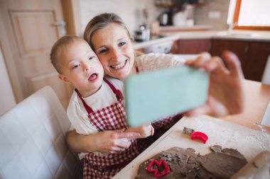 Down sendromlu çocuk annesiyle selfie pişirme zaman kapalı alarak.