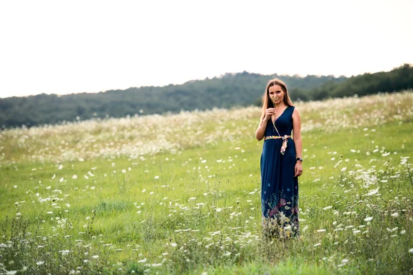Uma jovem mulher de pé na natureza em um dia de verão, cheirando flores. Espaço de cópia . — Fotografia de Stock