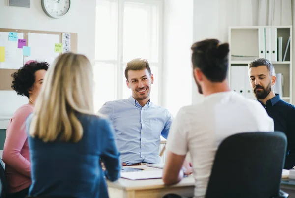 Gruppe junger Geschäftsleute sitzt am Tisch in einem modernen Büro und trifft sich. — Stockfoto