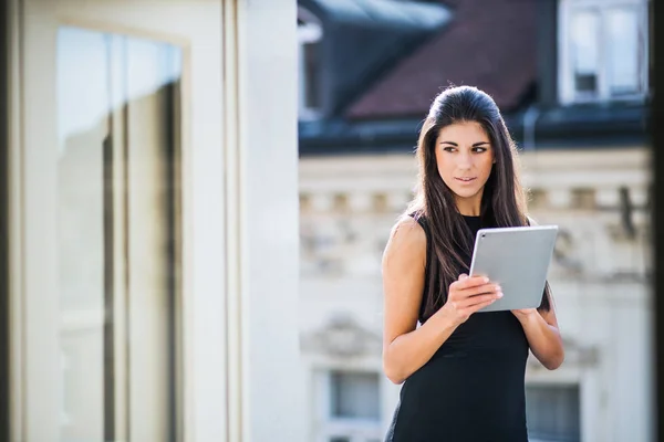 Ung affärskvinna med tablett står på en terrass utanför ett kontor i city. — Stockfoto