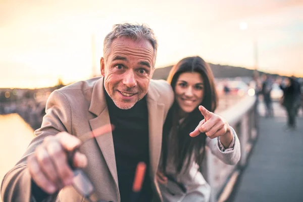 Emocionados socios de negocios hombre y mujer de pie junto a un río en la ciudad al atardecer . —  Fotos de Stock