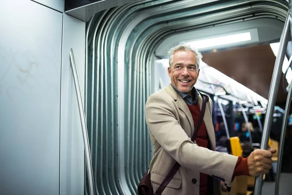 Uomo d'affari maturo con smartphone che viaggia in tram in città . — Foto Stock