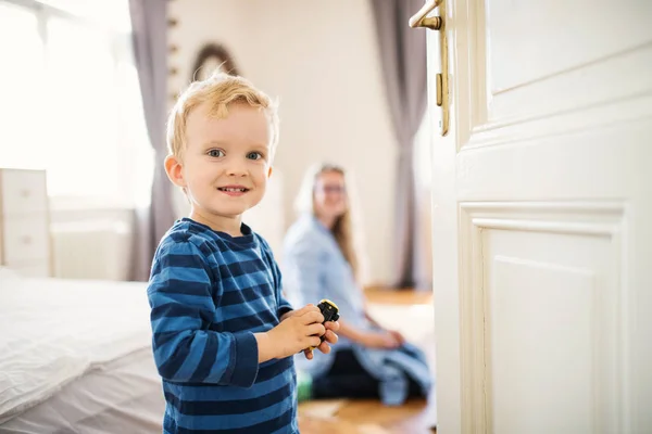 Um menino de criança com jovem mãe no fundo dentro de um quarto . — Fotografia de Stock