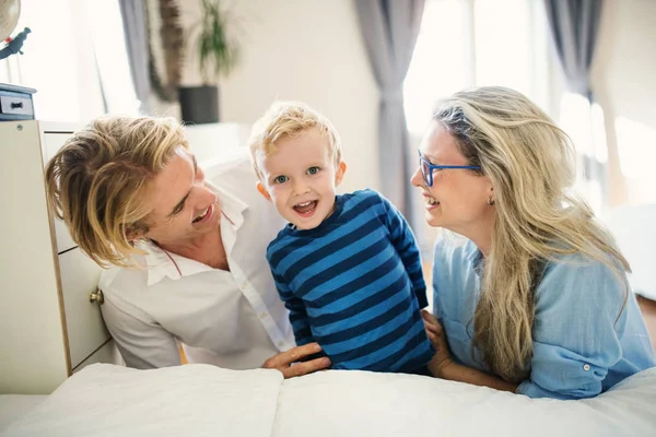 Young parents looking at their toddler son inside in a bedroom. — Stock Photo, Image