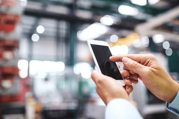 Närbild av kvinnliga händer i fabriken med smartphone. Kopiera utrymme. — Stockfoto