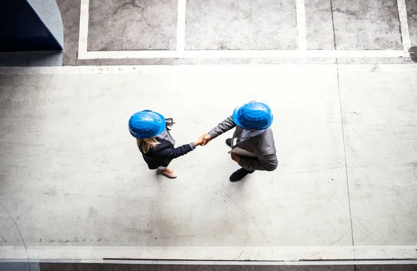 A top view of an industrial man and woman engineer in a factory, shaking hands. — Stock Photo, Image