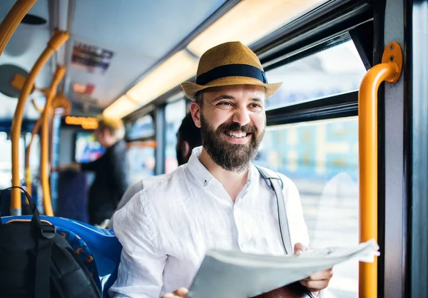 Hipster człowieka w autobusie w miasta, podróży do pracy i gazety. — Zdjęcie stockowe