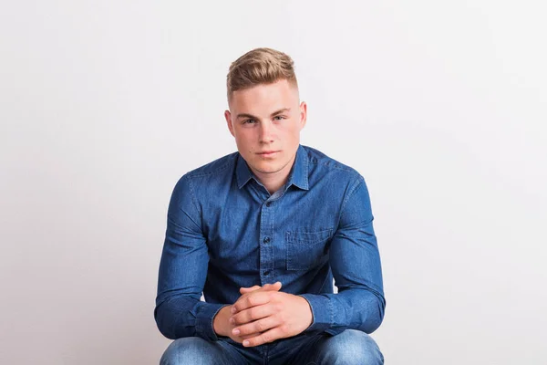 Portrait of a happy young man in a studio, sitting. — Stock Photo, Image